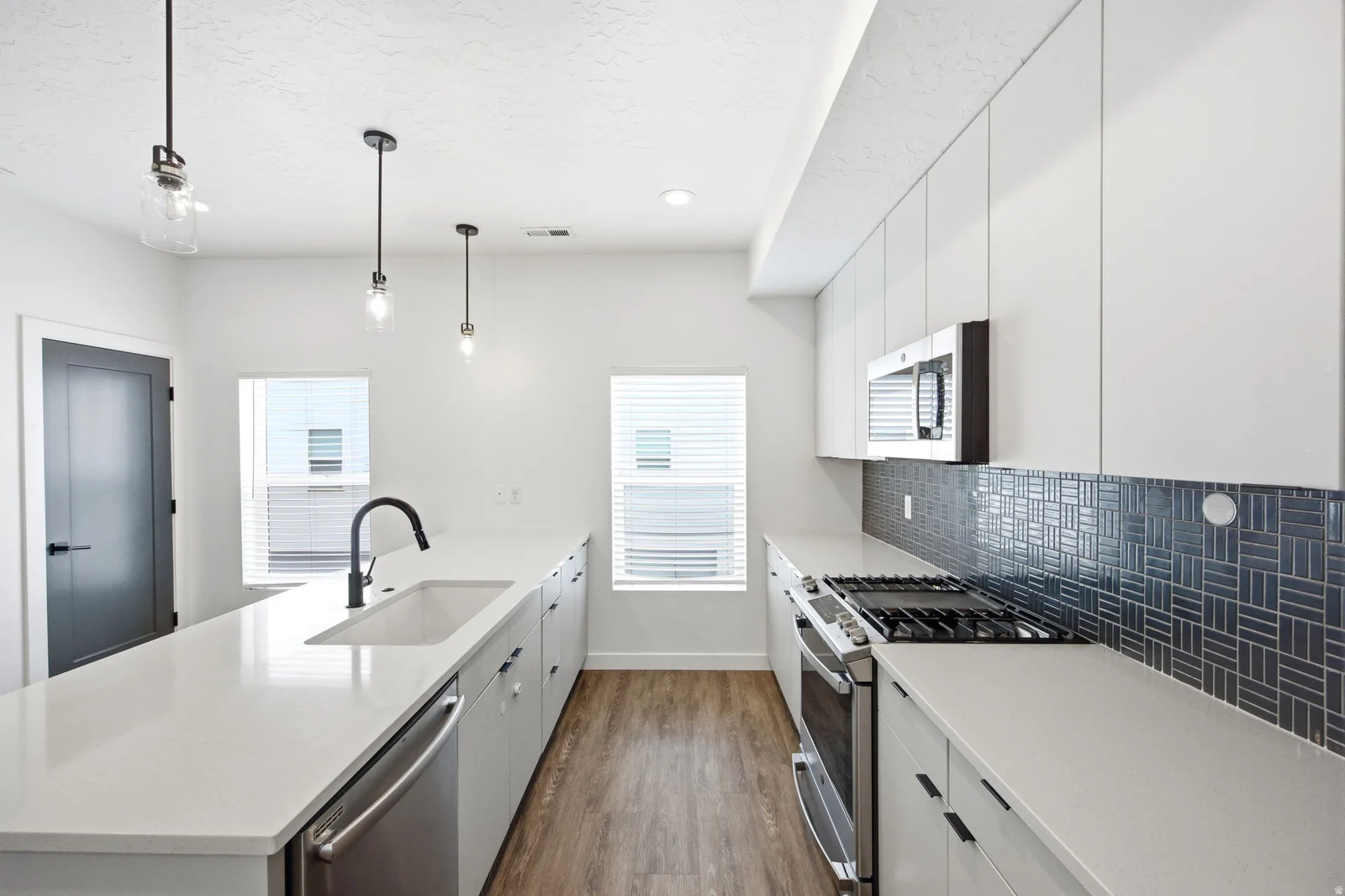 Modern kitchen featuring a large center island with an undermount sink and matte black faucet